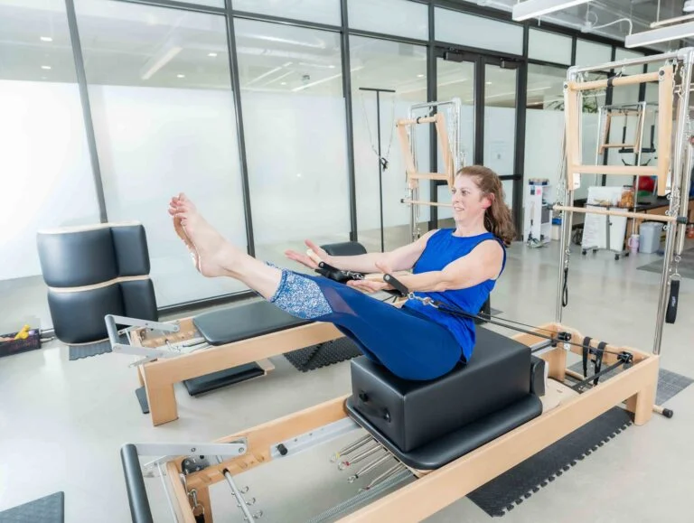 Instructor guiding a client through classical Pilates